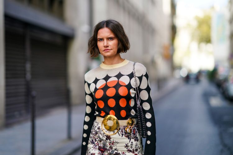 PARIS, FRANCE - OCTOBER 04: Marta Cygan wears a wool pullover with printed black orange and white dots, a belt with golden buckle, a white floral print colored skirt, a metallic bag, outside Paco Rabanne, during Paris Fashion Week - Womenswear Spring Summer 2021, on October 04, 2020 in Paris, France. (Photo by Edward Berthelot/Getty Images)