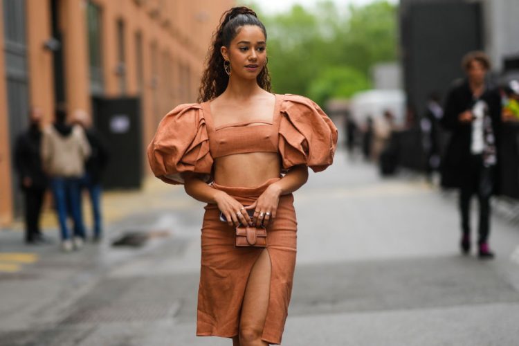 SAINT-DENIS, FRANCE - JUNE 30: Lena Mahfouf aka Lena Situations wears a salmon-pink square neck cropped top with oversized puffy gathered shoulders, a mini brown leather Jacquemus bag, a knee-length slit matching skirt, during Jacquemus "La Montagne" Show, at La Cite Du Cinema on June 30, 2021 in Saint-Denis, France. (Photo by Edward Berthelot/Getty Images)